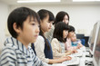 © amanaimages - Students studying on desktop computers in classroom