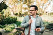 © bnenin - Smiling business man with smartphone outdoors, looking away.