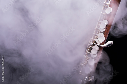 Fotografie, Obraz A piccolo flute from brown wood with silve plated keys in smoke on a black backg