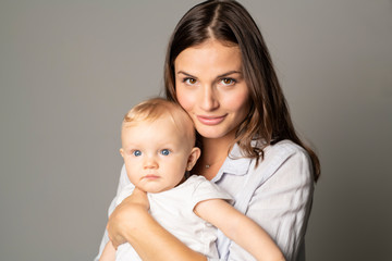 Wall Mural - A mother holdng his baby on studio gray background