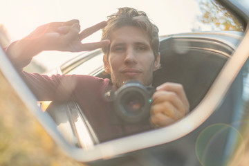 young driver taking a self portrait with professional camera in the car window  f