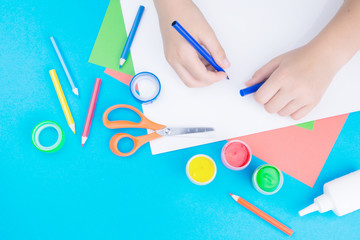 Color paper, paint and hands of a child drawing on paper