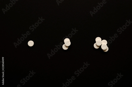 Fotografia Three handfuls of pills on black background, in the center