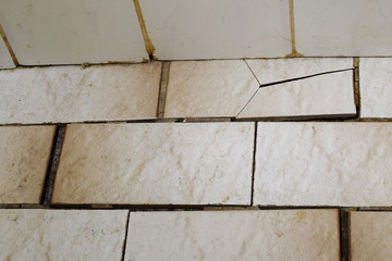 Cracked ceramic floor tile and seams in bad condition.