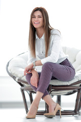 Poster - modern young young woman sitting in a comfortable chair