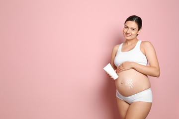 Wall Mural - Sun painted with body cream on pregnant woman's belly against color background. Space for text