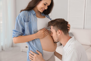 Poster - Young husband kissing his pregnant wife's tummy at home