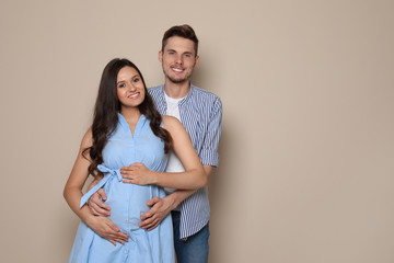 Wall Mural - Pregnant woman and her husband on color background. Space for text