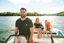 Man Driving Boat On Holiday With His Son Kids And His Wife