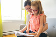 © Louis-Paul Photo - Mom with little girl reading book in sofa