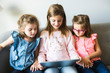 © Louis-Paul Photo - Three sisters girls sit on the sofa at home with tablet
