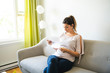 © Louis-Paul Photo - Young woman stressed because of bills sit on the sofa