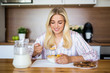 © Di Studio - healthy breakfast concept - young woman eating corn flakes with milk in modern kitchen