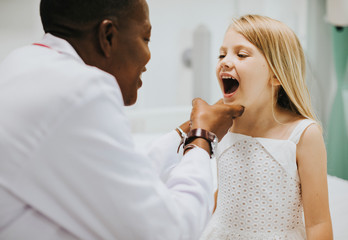 Wall Mural - Young girl showing a dentist her teeth