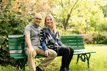 A Young couple sitting on bench at the park.