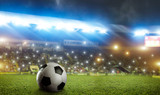 Fototapeta Sport - Football ball on green grass of the stadium field