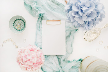 Wall Mural - Clipboard with copy space, turquoise blanket, colorful pastel hydrangea flower bouquet, woman fashion accessories on white background. Flat lay, top view mockup.