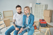 © LIGHTFIELD STUDIOS - happy young couple in tattoos sitting together and smiling at camera while making repairs in new house