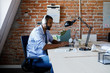 © LUMINA IMAGES - Young African businessman with headphones typing on his laptop at work.