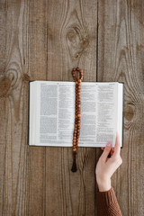 Wall Mural - cropped shot of woman with holy bible and beads on wooden tabletop