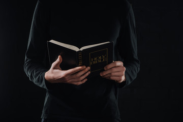 Poster - cropped shot of priest reading holy bible isolated on black