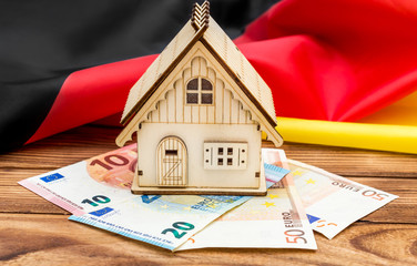 Wall Mural - Model of house with euro and German flag on the wooden table.