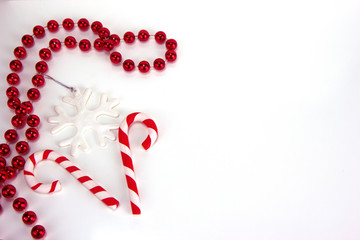 Wall Mural - Two red and white candy canes, snowflake and red necklace. Christmas and New Year holiday background concept. Blank space for greetings.