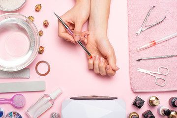 Nail care. beautiful women hands making nails painted with pink gentle nail polish on a pink background. Women's hands near a set of professional manicure tools. Beauty care