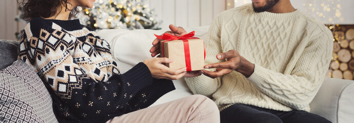 Handsome man surprising girl with Christmas gift