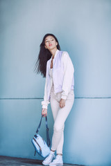 Woman Trendy Fashion. Attractive sporty asian girl in full length with elegant hairstyle and perfect soft colorful makeup. Female with perfect slim body in sport trendy clothes against fancy wall on