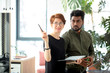 © alfa27 - two business partners standing in office building and talking about deals, woman showing coworker his new office place