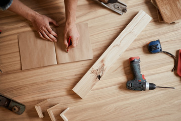 DIY concept, close up . Woodworking and crafts tools. Handicraft Carpentry. Top view of male Designer s hands working in his workshop, making a draw of custom furniture for rich people.