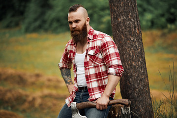 Wall Mural - Lumberjack worker sitting in forest resting after hard work