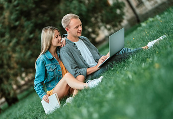 The guy and the girl look at the laptop together.