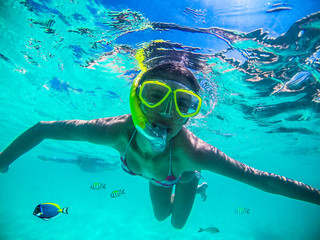 Young woman snorkeling in the tropical Oliveli island , Maldives.