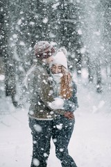 Wall Mural - couple of young people in love walks in the winter forest. play with snow before christmas.