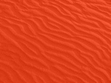 Texture Of Red Sand Waves On The Beach Or In The Desert. The Ripples Of The Sand Is Diagonal.