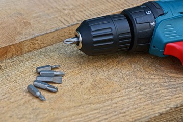 screwdriver and set of gray iron bits on a brown wooden board