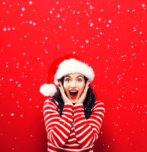 Happy Young Woman With Santa Hat On A Red Background