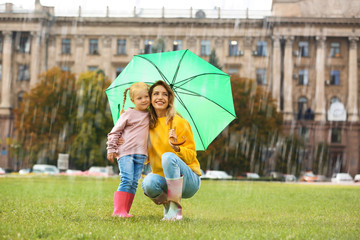 Wall Mural - Happy mother and daughter with umbrella in park