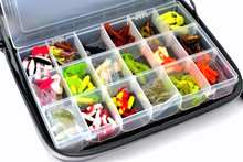A Box With A Variety Of Silicone Baits Lies In A Fishing Bag, White Background Close-up