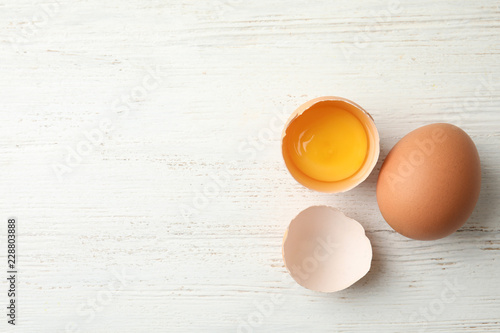 Fotografía Raw chicken eggs on wooden background, top view. Space for text