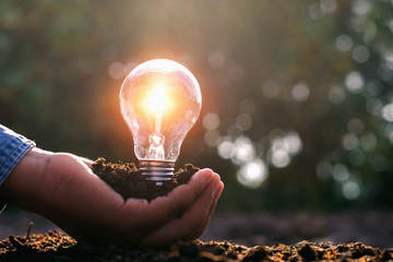 lightbulb on hand and sunshine. solar energy concept idea