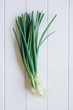 bundle of scallions or spring onions, top view on white wooden table