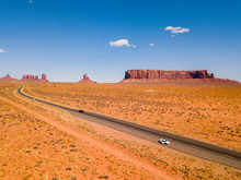 July 30, 2018. Monument Valley National Park, Utah, USA. White Ford Mustang Parked By The Side Of The Road At Monument Valley National Park With An Amazing View On The Infinite Road Through The Desert