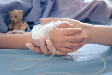 Mother holding child's hand who fever patients in hospital to give encouragement