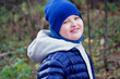 © irinashamanaeva - lifestyle, child autistic in blue hat and blue jacket playing with wilted leaves in autumn Park for a walk with family