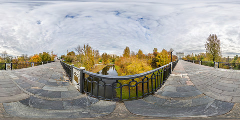 Wall Mural - full seamless spherical cube panorama 360 degrees angle view on pedestrian bridge across small river in autumn city park in equirectangular projection, ready for AR VR virtual reality content