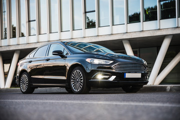 Luxurious black sedan car in front of modern building