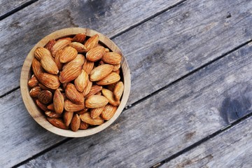 Almond nut in wooden bowl on wood tabla background, copy space 